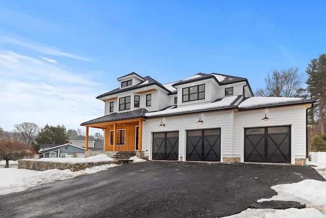 view of front of house with a standing seam roof, an attached garage, driveway, and metal roof