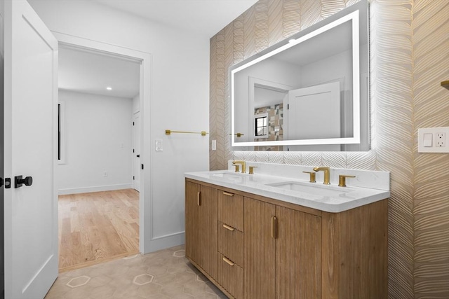 bathroom with a sink, baseboards, double vanity, and tile patterned floors