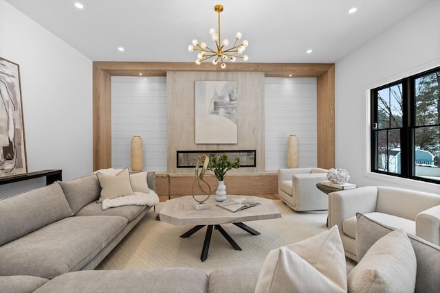 living room with a glass covered fireplace, an inviting chandelier, and recessed lighting