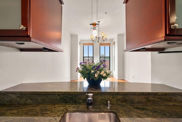 567 Tremont St Unit 20, Boston, MA 02118 - kitchen with dark stone countertops, a chandelier, reddish brown cabinets, and hanging light fixtures