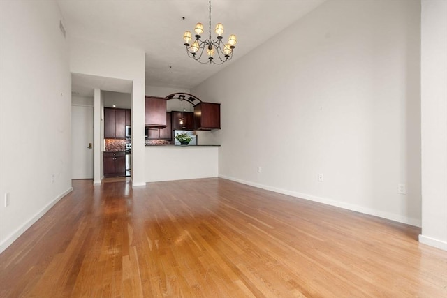 567 Tremont St Unit 20, Boston, MA 02118 - unfurnished living room with a chandelier, light wood-style flooring, and vaulted ceiling
