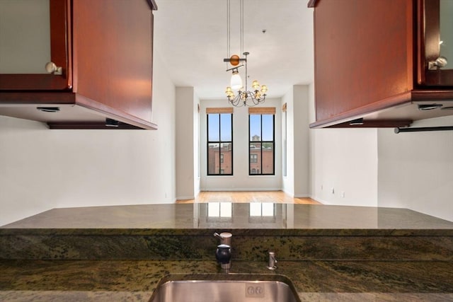 567 Tremont St Unit 20, Boston, MA 02118 - kitchen with dark stone counters, a chandelier, reddish brown cabinets, and pendant lighting