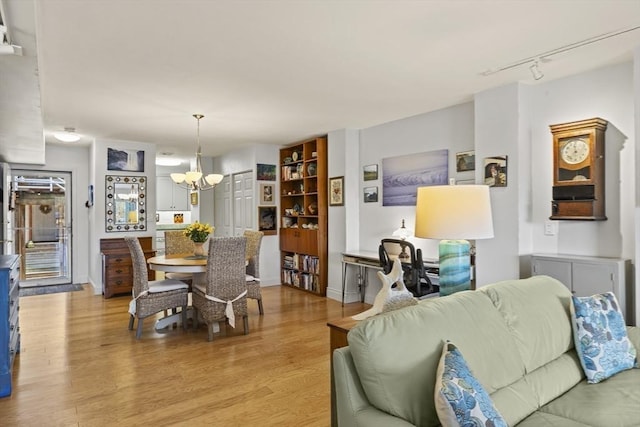 dining space featuring track lighting, a notable chandelier, and light hardwood / wood-style flooring