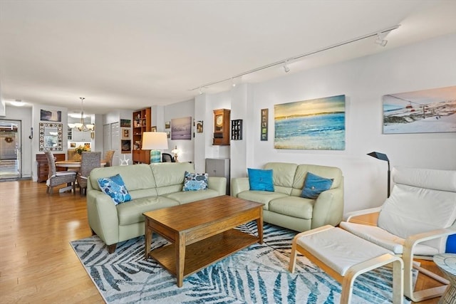 living room featuring track lighting, a chandelier, and light hardwood / wood-style floors