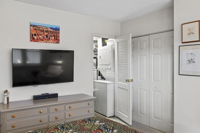 bedroom featuring stacked washer / drying machine, a closet, and ensuite bath