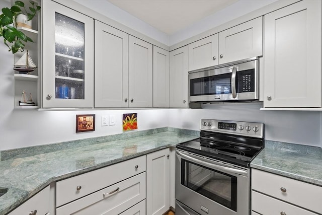 kitchen with light stone countertops, white cabinetry, and appliances with stainless steel finishes