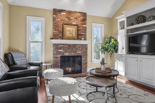 living room featuring a fireplace, dark hardwood / wood-style floors, lofted ceiling, and a healthy amount of sunlight