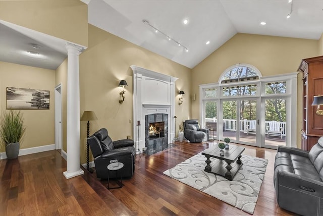 living room with decorative columns, rail lighting, high vaulted ceiling, and dark hardwood / wood-style flooring