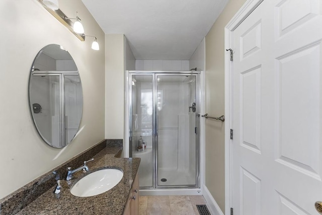 bathroom with a shower with shower door, vanity, and tile patterned floors