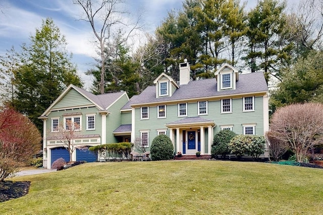 view of front of house featuring a front yard, an attached garage, and a chimney