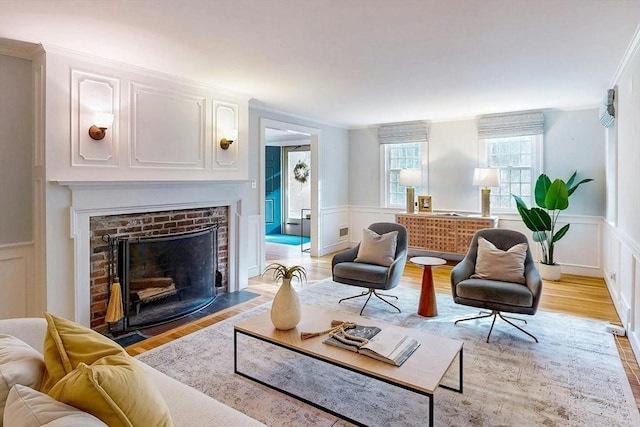 living room with wainscoting, a fireplace, and light wood-type flooring