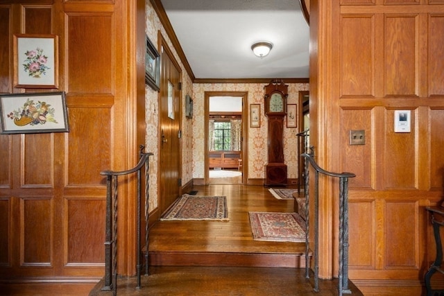 foyer entrance featuring hardwood / wood-style floors, wooden walls, and crown molding