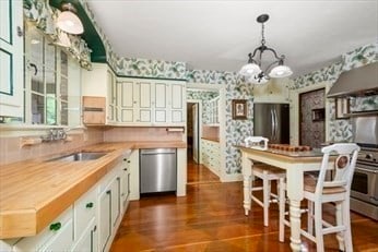 kitchen with dark hardwood / wood-style flooring, pendant lighting, wood counters, stainless steel appliances, and a chandelier