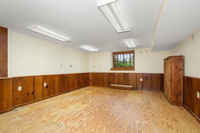 unfurnished room with wood walls and wood-type flooring