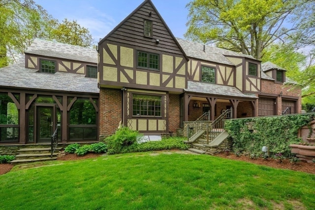 rear view of house featuring a lawn and a garage