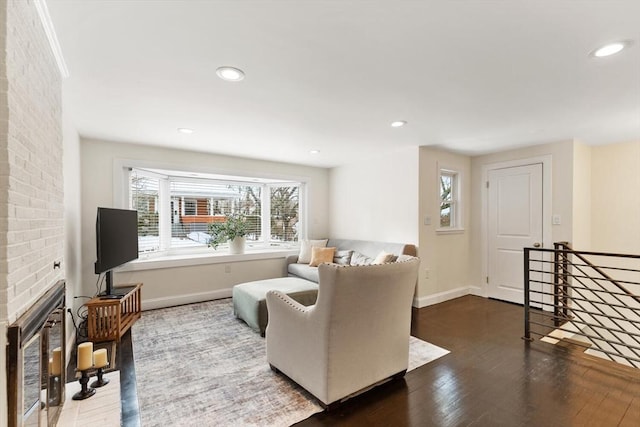 living room with a healthy amount of sunlight, a brick fireplace, and dark hardwood / wood-style floors