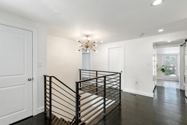 stairway featuring hardwood / wood-style floors and a notable chandelier