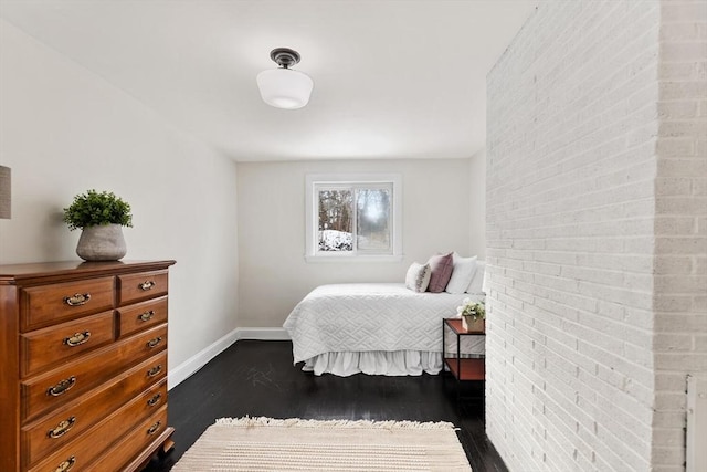 bedroom featuring brick wall and dark wood-type flooring