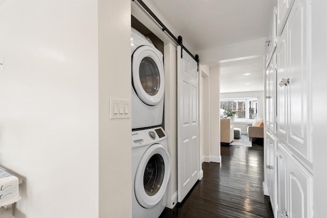 washroom with dark hardwood / wood-style floors, stacked washer and clothes dryer, and a barn door