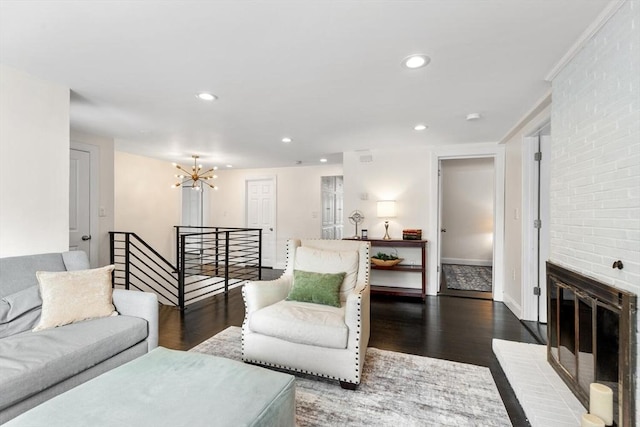 living room featuring a brick fireplace, dark hardwood / wood-style floors, and a chandelier