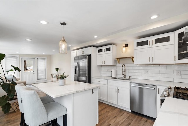 kitchen with pendant lighting, sink, white cabinets, a center island, and stainless steel appliances