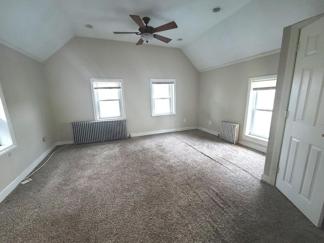 carpeted spare room with radiator, a healthy amount of sunlight, and lofted ceiling