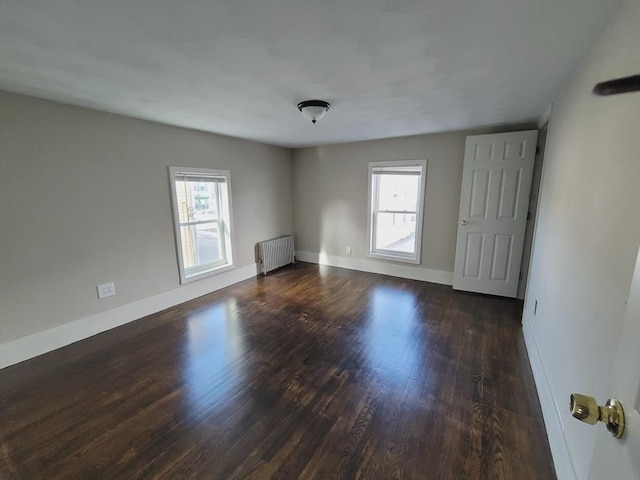 unfurnished room with radiator, plenty of natural light, and dark wood-type flooring