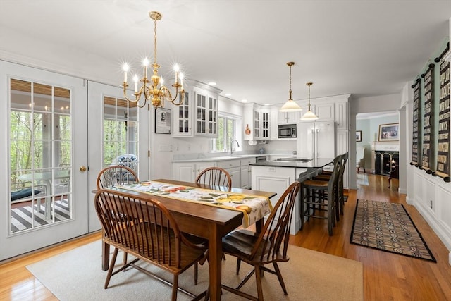 151 River Rd, West Newbury, MA 01985 - dining space with a chandelier, light wood-type flooring, a warm lit fireplace, and recessed lighting