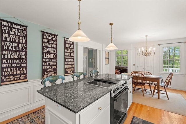 151 River Rd, West Newbury, MA 01985 - kitchen with range with electric stovetop, light wood-style flooring, a chandelier, and white cabinetry