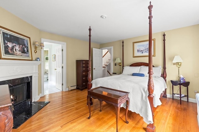 151 River Rd, West Newbury, MA 01985 - bedroom featuring baseboard heating, wood finished floors, a high end fireplace, baseboards, and ensuite bath