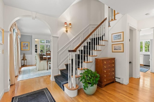 151 River Rd, West Newbury, MA 01985 - stairway with arched walkways, a baseboard heating unit, wood finished floors, decorative columns, and a wainscoted wall