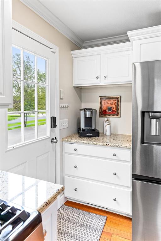 1380 Newman Ave, Seekonk, MA 02771 - kitchen with stainless steel appliances, crown molding, light wood finished floors, white cabinetry, and light stone counters