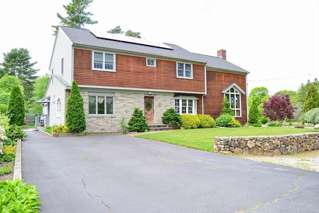 110 Mayflower Ridge Dr, Wareham, MA 02571 - view of front of house featuring a chimney, solar panels, a front yard, and stone siding