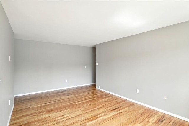 spare room featuring baseboards and light wood-type flooring