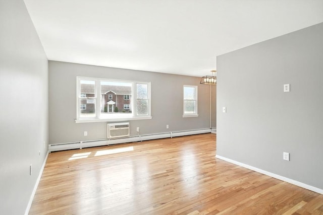unfurnished living room with baseboards, a baseboard radiator, a notable chandelier, and light wood-type flooring