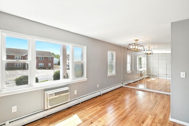 empty room featuring baseboards, a baseboard radiator, light wood-style flooring, and a chandelier