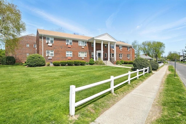 view of front of property featuring brick siding, fence, and a front lawn
