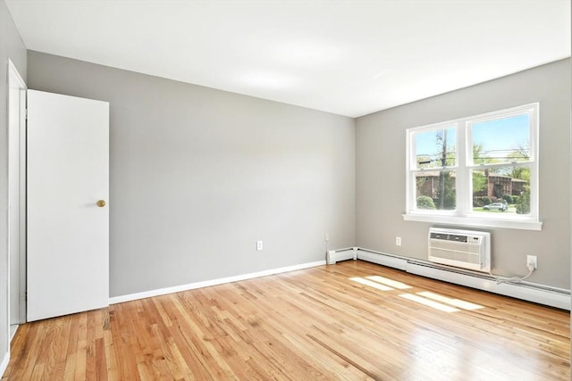 empty room with baseboards, a wall mounted air conditioner, light wood-style flooring, and a baseboard heating unit