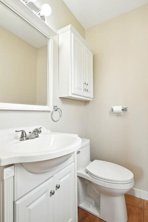 half bath featuring tile patterned flooring, toilet, and vanity