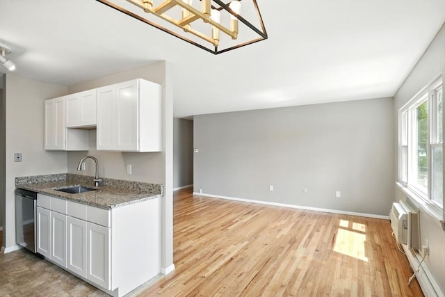 kitchen with a sink, white cabinetry, light wood-type flooring, stainless steel dishwasher, and a wall mounted AC
