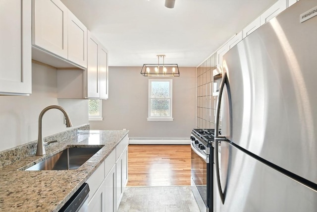 kitchen with a sink, white cabinets, appliances with stainless steel finishes, and baseboard heating