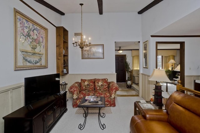 living room with a wainscoted wall, beamed ceiling, and an inviting chandelier