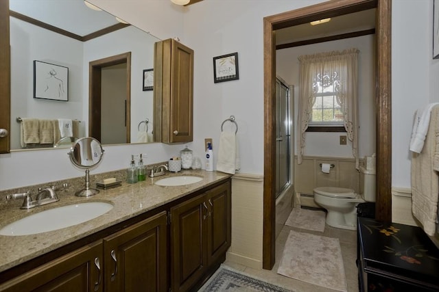 full bathroom with a sink, toilet, double vanity, and crown molding