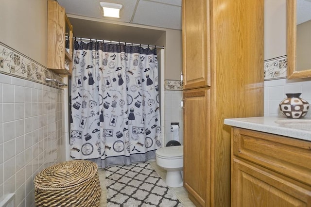 full bath featuring vanity, curtained shower, tile walls, toilet, and tile patterned floors