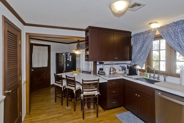 kitchen with visible vents, a sink, stainless steel appliances, light wood finished floors, and light countertops