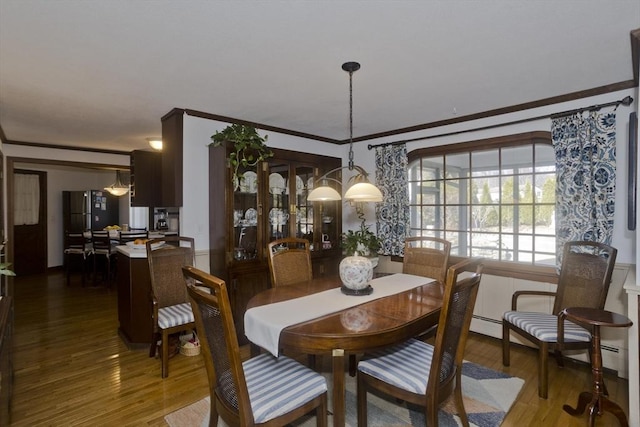 dining space with wood finished floors, a chandelier, and crown molding