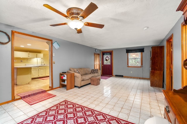 tiled living room with ceiling fan, sink, and a textured ceiling