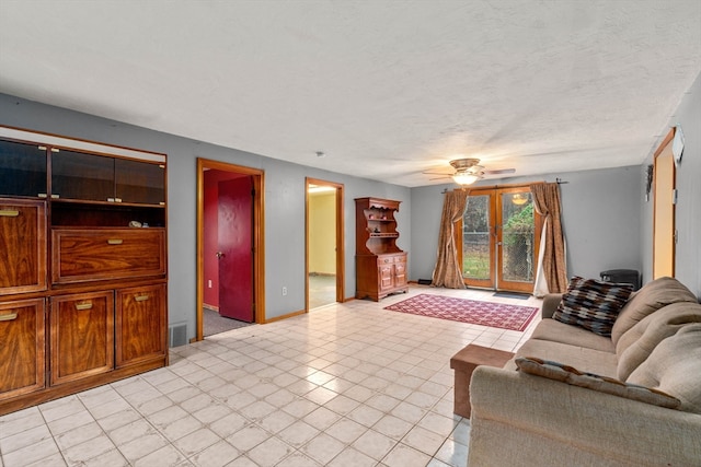 living room featuring ceiling fan, a textured ceiling, and french doors