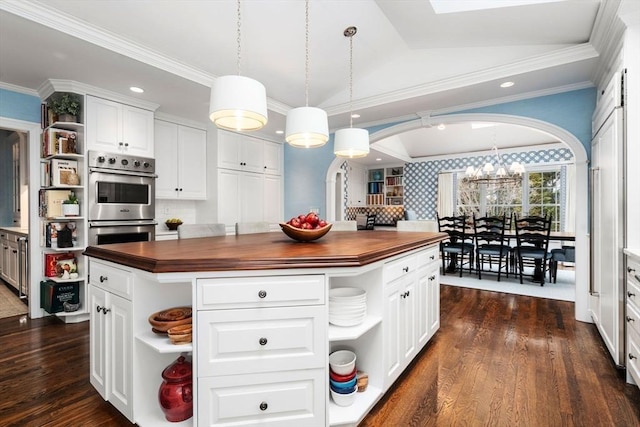 kitchen featuring arched walkways, open shelves, butcher block counters, double oven, and dark wood-type flooring