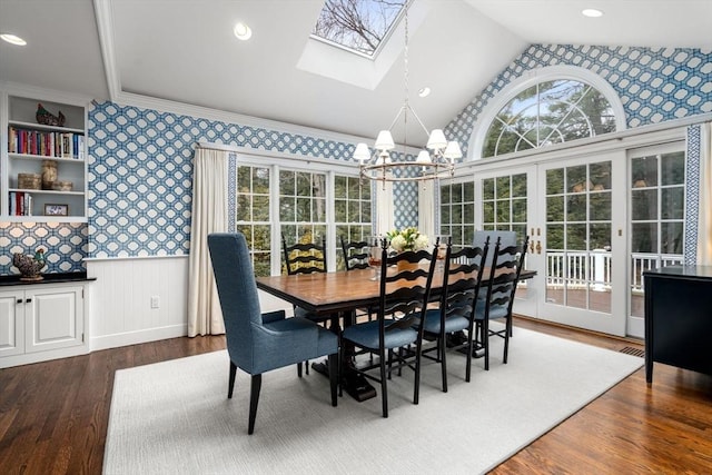 dining room featuring dark wood-style floors, a wainscoted wall, a notable chandelier, lofted ceiling, and wallpapered walls